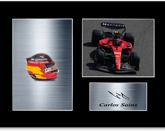Könnte beinhalten: Gerahmter Druck mit einem Formel-1-Rennwagen, einem Rennhelm und einer Unterschrift. Der Helm hat rote, gelbe und schwarze Akzente. Das Auto ist rot mit schwarzen Reifen. Die Unterschrift lautet "Carlos Sainz".