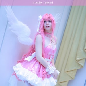May include: A person in a pink cosplay outfit with white angel wings. The outfit includes a pink dress with white trim, a matching choker, and a pink wig. The text "Nostalgia Dorothy Wings" and "Cosplay Tutorial" are at the top of the image.