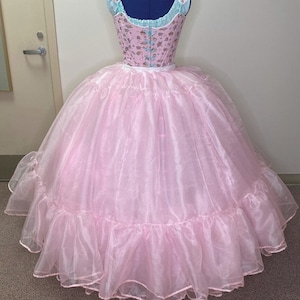 May include: A pink tulle petticoat with multiple layers of ruffles. The petticoat is designed to create a full, voluminous skirt.