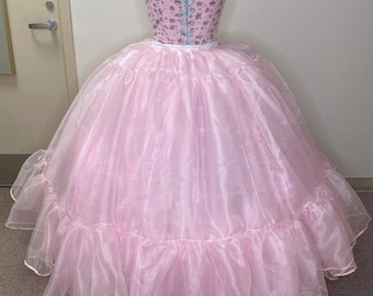 May include: A pink tulle petticoat with multiple layers of ruffles. The petticoat is designed to create a full, voluminous skirt.