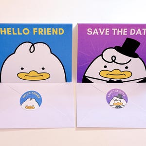 May include: Two greeting cards with cartoon duck illustrations. One card reads "HELLO FRIEND" on a blue background, the other says "SAVE THE DATE" on a purple background. White envelopes with matching stickers complete the set.