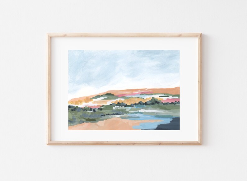 May include: Abstract landscape painting in a light wooden frame. The artwork features a blend of colors, including light blue, peach, green, and navy. The brushstrokes create a textured effect, depicting a serene outdoor scene with a sky and land.
