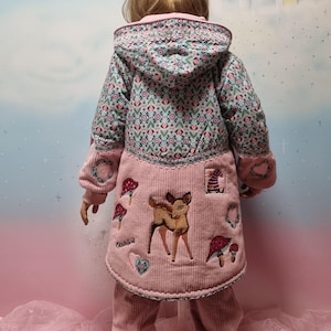 May include: A pink corduroy jacket with a blue and green patterned hood and a deer and mushroom applique. The jacket has a pink corduroy trim and a zipper closure.