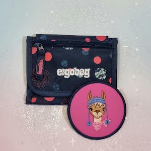 Könnte beinhalten: Ein dunkelblaues Portemonnaie mit Punkten und dem in Weiß gestickten Schriftzug ergobag. Ein runder, pinkfarbener Aufnäher mit einem gestickten Lama, das eine blaue Mütze und einen pinken Schal trägt, liegt vor dem Portemonnaie mit Reißverschluss.