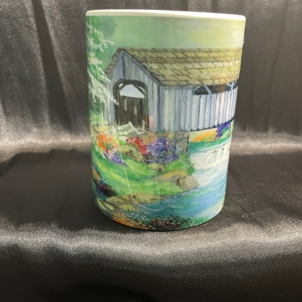 Covered bridge painted by mouth artist on coffee and tea mug.