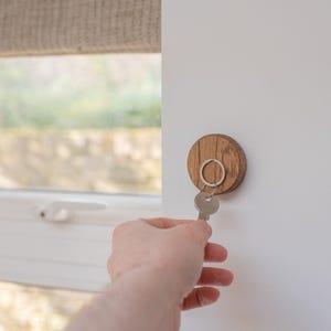 Oak magnetic key holder on wall with hand placing key onto it