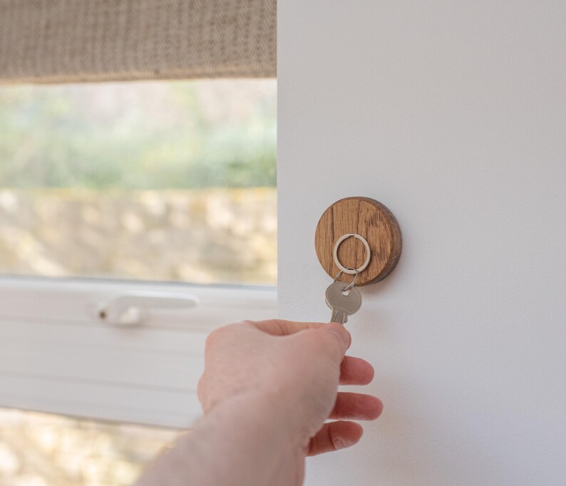 Oak magnetic key holder on wall with hand placing key onto it