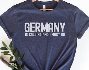 Puede incluir: Una camiseta azul marino jaspeada con el texto "GERMANY IS CALLING AND I MUST GO" en blanco.