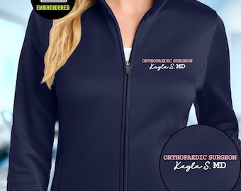 Geborduurd jack met volledige ritssluiting voor orthopedisch chirurg, met gepersonaliseerde naam en opdruk 'Doctor of Medicine' (MD) fleece.