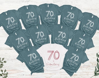 May include: Ten teal blue t-shirts with white text that says "70th Birthday Crew". One white t-shirt with white text that says "70 & Fabulous" in pink.
