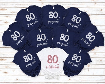 May include: Nine navy blue t-shirts with white text that reads "80 party crew" and one white t-shirt with pink text that reads "80 & fabulous".