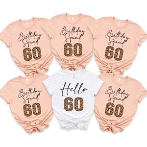 May include: Five t-shirts with the text "Birthday Squad 60" in black script on a peach background. One t-shirt is white with the text "Hello 60" in black script. The number 60 on all shirts is a leopard print.