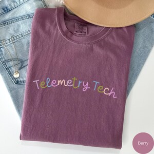 May include: A purple t-shirt with the text "Telemetry Tech" in colourful lettering. The shirt is made of a soft, comfortable material.