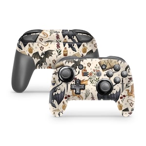 May include: Two wireless game controllers featuring a cream-colored skin with a repeating pattern of black dragons, open books, glass potion bottles, daggers, and botanical illustrations. The controllers have black buttons, joysticks, and triggers.