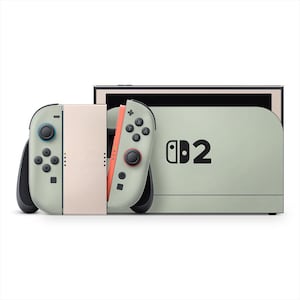 以下が含まれることがあります： ライトグリーンとピーチカラーのNintendo Switchコンソール。2つの取り外し可能なコントローラーが付いています。コントローラーには黒いボタンとジョイスティックがあります。コンソールには数字の「2」が印刷されています。