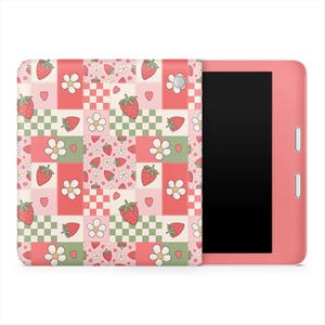 以下が含まれることがあります： イチゴ、花、ハート模様のカバーが付いたピンク色のタブレット。カバーは、赤、ピンク、緑の正方形のパッチワークデザインです。タブレットの画面は黒です。