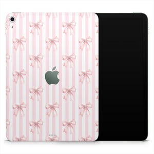 May include: An Apple iPad with a pink and white striped design. The back of the iPad is covered in a pattern of pink bows and vertical stripes. The Apple logo is visible in the center.