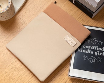 May include: A beige and brown fabric Kindle case with a small leather patch that says "Signet Tech".