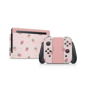 Peut inclure: Console et manettes Joy-Con Nintendo Switch roses avec un motif de fraises.