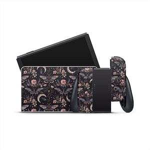 Peut inclure: Une console de jeu noire et ses accessoires avec un motif floral sombre avec des papillons, des lunes et des fleurs. L'ensemble comprend une console, une station d'accueil et deux manettes, toutes avec le même motif.