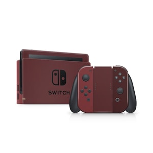 May include: A maroon Nintendo Switch console and controllers. The console is in the background with the word "SWITCH" printed on the front. The controllers are in the foreground, with black grips and buttons. The background is white.