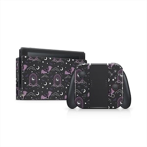 May include: A black Nintendo Switch console and controllers with a decorative skin featuring a repeating pattern of purple bats, moons, clouds, and gothic arches on a dark background. The controllers are black.