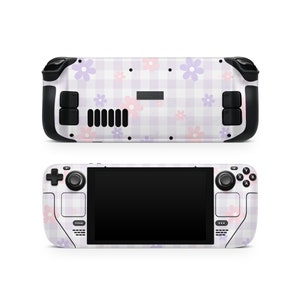 May include: A white and purple handheld gaming console with a floral and checkered pattern. The console has a black screen and buttons.