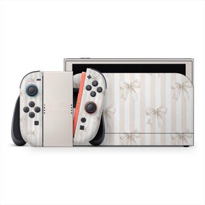 Könnte beinhalten: Eine Nintendo Switch-Konsole mit einem individuellen Skin mit einem cremefarbenen und weißen Streifenmuster, das mit zarten Schleifen verziert ist. Die Joy-Con-Controller haben schwarze Akzente und farbige Knöpfe.