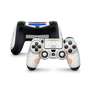 May include: Two white and black game controllers with a floral pattern in pink and blue. The controllers have buttons and joysticks. The background is white.