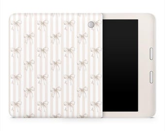 Op de afbeelding: Een witte e-reader met een crèmekleurige hoes met een patroon van crèmekleurige strikken op een gestreepte achtergrond. De e-reader heeft een zwart scherm en knoppen aan de zijkant.