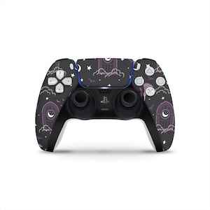 Puede incluir: Un mando negro de PlayStation 5 con una piel personalizada con un diseño gótico. La piel incluye ventanas arqueadas moradas, nubes, estrellas y murciélagos. El mando tiene joysticks y botones negros.