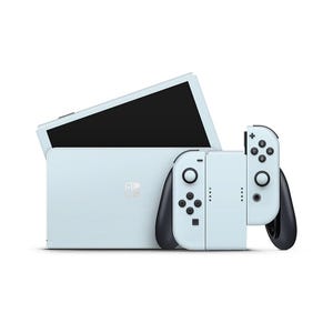 May include: A light blue video game console with detachable controllers. The console has a black screen and a white logo. The controllers are light blue with black accents and buttons. The console is designed for gaming.