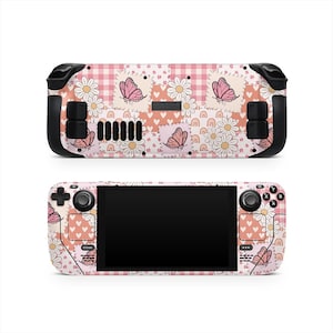 Puede incluir: Dos consolas de juegos Steam Deck, una encima de la otra, con una piel personalizada. La piel tiene un diseño de patchwork con cuadros rosas, margaritas, mariposas y corazones. Las consolas son negras con botones negros y una pantalla negra.