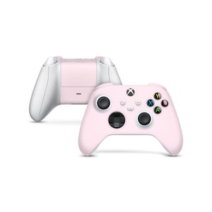 May include: A pink Xbox wireless controller with white accents. The controller has a standard layout with buttons labelled A, B, X, Y, and a directional pad.