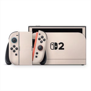 May include: A beige Nintendo Switch console with matching Joy-Con controllers. The controllers have black buttons and joysticks, with one featuring orange accents. The console displays the number "2" next to the Nintendo Switch logo.