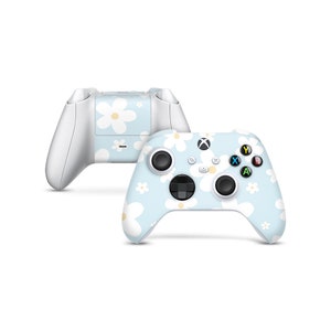 May include: A light blue Xbox controller with a white daisy pattern. The controller has a white faceplate and white buttons.