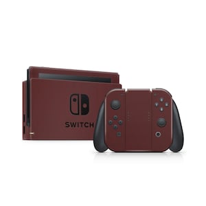 Può includere: Una console Nintendo Switch color bordeaux con controller neri. La console è esposta con la dock e i controller. La parola "SWITCH" è stampata in bianco sulla console.