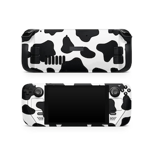 May include: Two Steam Deck gaming consoles, one above the other, with a black and white cow print design. The top console shows the back, and the bottom console shows the front with a black screen and buttons.