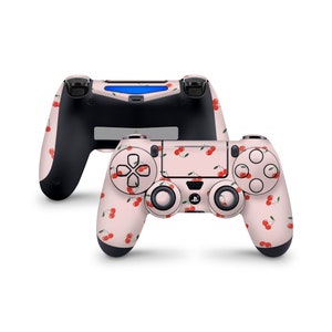 May include: A pink and white PlayStation 4 controller with a cherry pattern. The controller has a black faceplate and black buttons.