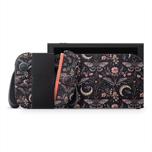 May include: A black Nintendo Switch console with a decorative skin featuring a dark floral and butterfly pattern. The Joy-Cons have a matching design with black buttons and a coral-colored rail. The dock also has the same design.