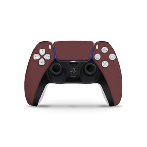 Może przedstawiać: Bezprzewodowy kontroler PlayStation 5 DualSense w kolorze brązowym z białymi akcentami i czarnymi przyciskami.