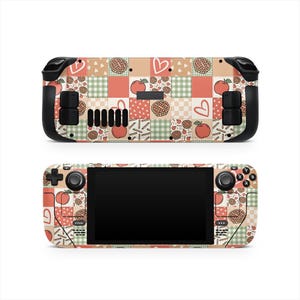 Puede incluir: Dos consolas Steam Deck, una encima de la otra, con un diseño de patchwork con gráficos de manzanas, corazones y tartas. La combinación de colores incluye tonos melocotón, rojo, verde y crema, creando una estética otoñal acogedora.