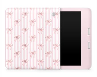 Op de afbeelding: Een roze tablet met een hoes met een patroon van roze strikken op een wit gestreepte achtergrond. De tablet heeft een zwart scherm en een roze frame met twee knoppen aan de zijkant.