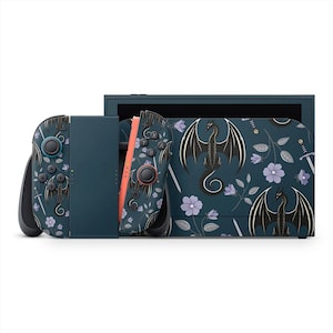 Könnte beinhalten: Eine teal Nintendo Switch-Konsole mit passenden Joy-Con-Controllern. Konsole und Controller zeigen ein Drachen- und Blumenmuster in Schwarz und Lila. Das Design umfasst Schwerter und Blumen auf einem dunkelblauen Hintergrund.
