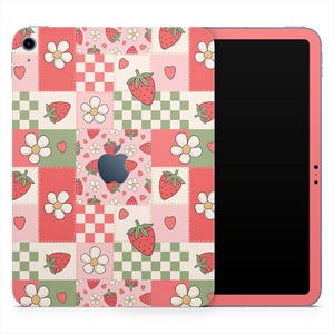 May include: A pink tablet with a colorful patchwork design featuring strawberries, flowers, hearts, and checkered patterns. The tablet has a black screen and a pink frame. The design is reminiscent of a quilt.