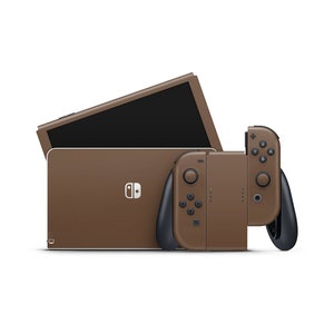 以下が含まれることがあります： 茶色のニンテンドースイッチ本体と、それに合わせた茶色のJoy-Conコントローラー。本体は閉じており、画面はオフになっている