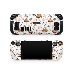 May include: A white handheld gaming console with a floral and mushroom pattern. The design includes brown mushrooms, pink flowers, and butterflies. The console has black control buttons and a black screen.