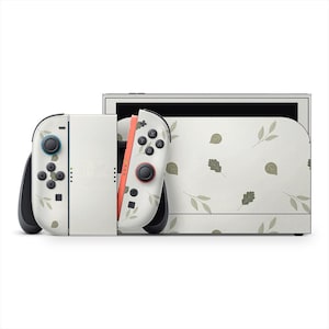 May include: A white Nintendo Switch console with a leaf pattern design. The Joy-Con controllers feature a matching leaf pattern and black buttons. The console has a white screen and a black frame.