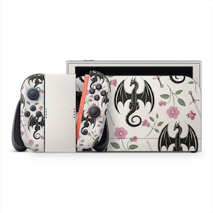 May include: A white Nintendo Switch console with a dragon and floral design. The Joy-Cons and console feature a repeating pattern of black dragons, pink flowers, and green leaves. The console is white with a light orange Joy-Con.