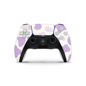 May include: A white and purple PlayStation 5 controller with a cow print design.